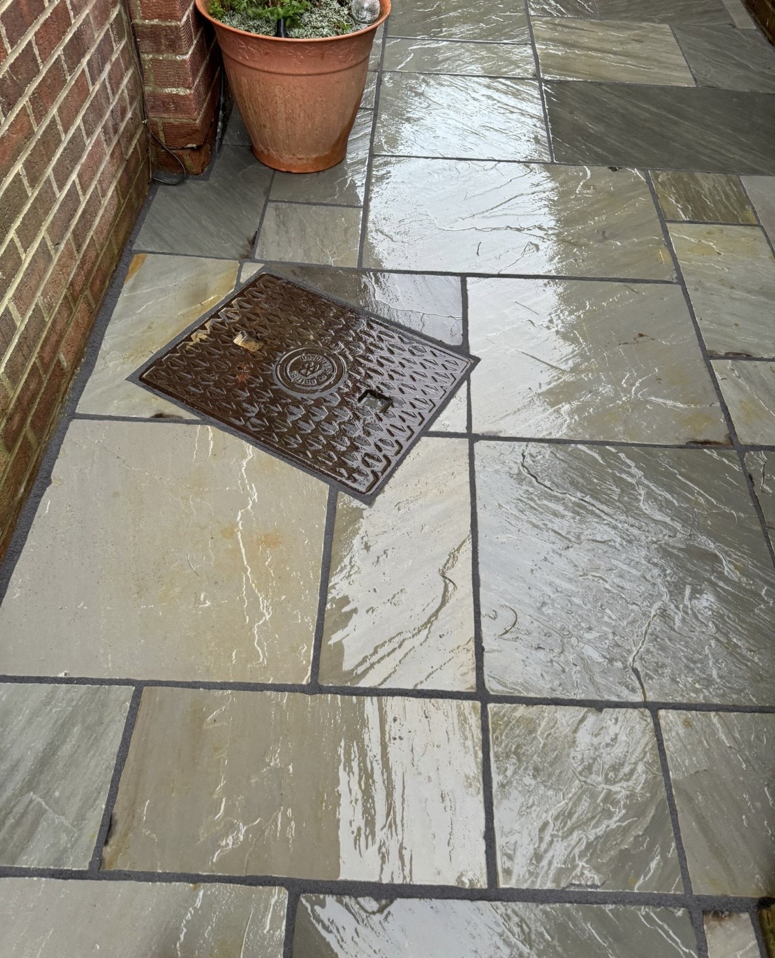 Wet natural stone patio paving with recessed inspection cover