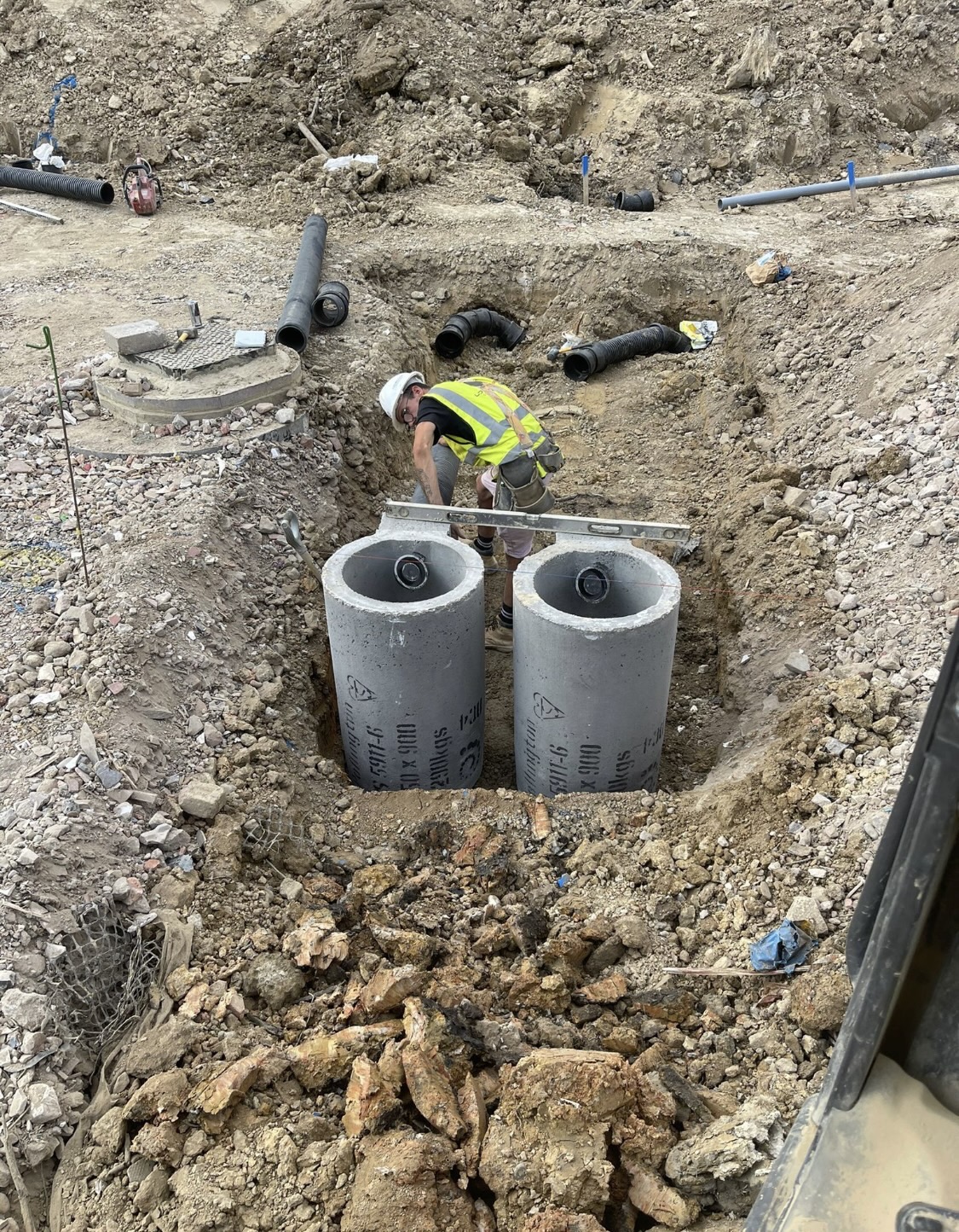 Groundworker setting level on twin concrete manhole rings
