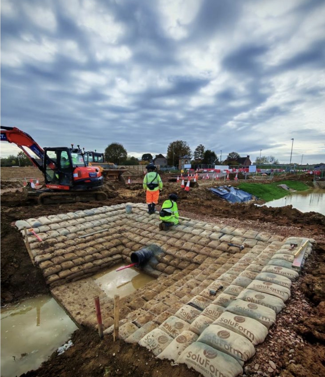 SoluForm sandbag headwall structure with drainage pipe on a rural site