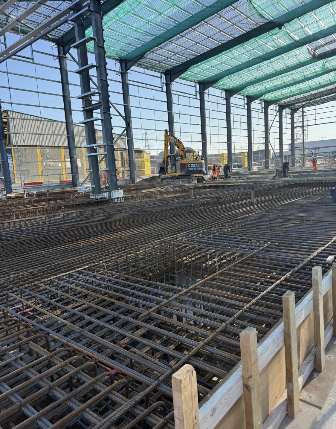 Reinforcement grids and excavator working inside a steel frame structure