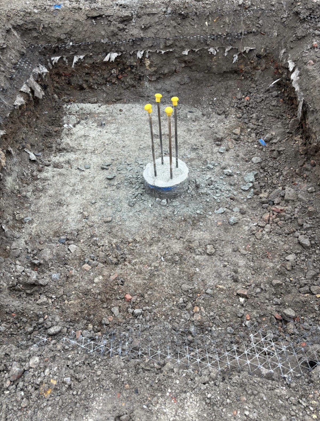 Concrete pad foundation with anchor bolts set in an excavated pit